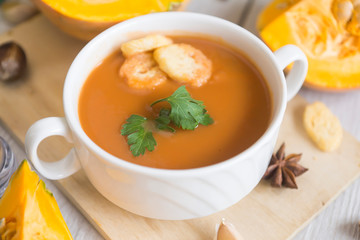 umpkin puree soup, pumpkin, spices on a wooden white background.