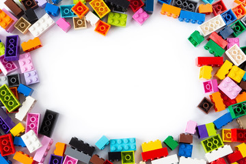 Obraz premium Close-up of a cluttered pile of colorful Lego bricks viewed from above with place for content or text in the middle. Isolated on white background, top view. Copy space.