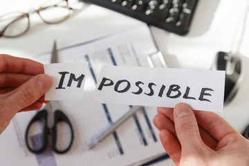 Fototapeta premium Businessman hands cutting the word impossible, letters im so it become possible