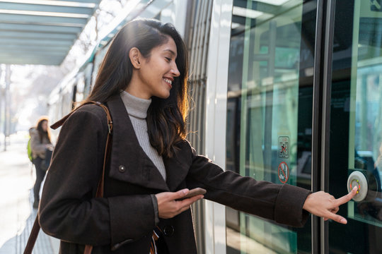 Smiling young woman pushing the button at a tram