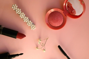 Beauty products and fashionable accessories on a pale pink background: blush, mascara, highlighter,...