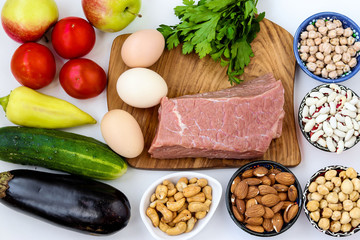 Flexitarian diet with fresh vegetables, raw meat, eggs, legumes, nuts, fruit on white background