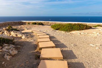 A path among the rocks to admire the blue sea on the northern cape of Cavalleria on the island of Minorca. Spain