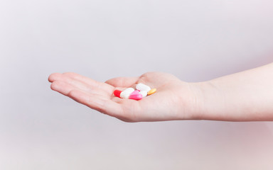hand holding multiple colors pills isolated on white background