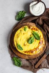Crepes roll with spinach, chicken and cream cheese baked with bechamel sauce on a wooden plate, light grey concrete background. Homemade food. Tasty breakfast.