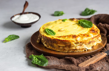 Crepes roll with spinach, chicken and cream cheese baked with bechamel sauce on a wooden plate, light grey concrete background. Homemade food. Tasty breakfast.