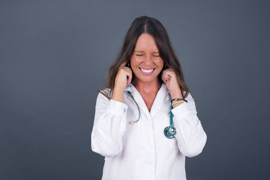 Stop making this annoying sound! Headshot of stressed out young doctor woman, plugging ears with fingers, irritated with loud noise coming from neighbors who live above her.