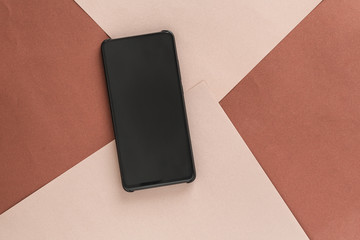 black smartphone on light and dark brown paper