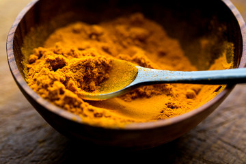 Close up view of turmeric in wooden bowl