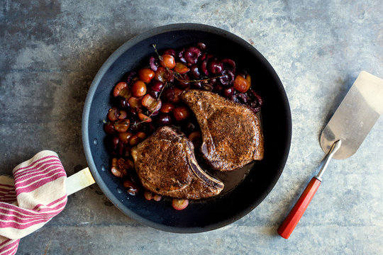 Directly above view of sauteed pork chops with cherries