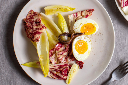 Salad with egg and anchovies placed in plate