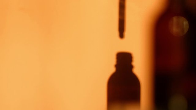 Glass bottle with dropper shadow. Oils drop from pipette. Copy space. Cosmetic minimalism 