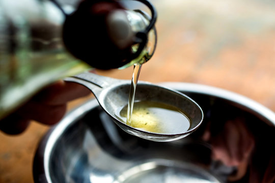 Selective focus of olive oil pouring into spoon