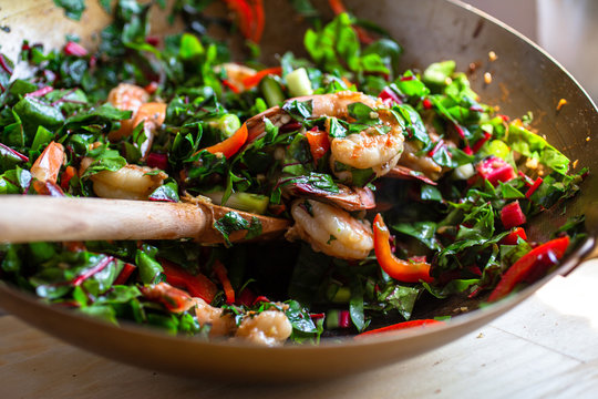 Stir fried shrimps with amaranth, red pepper and cilantro in wok