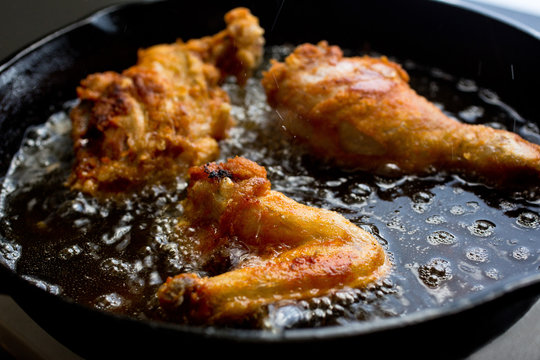 Close up view of chicken wings and legs frying in oil