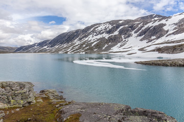 snow mountains surrounded by clouds in norwegian fiord reflection in water selective focus