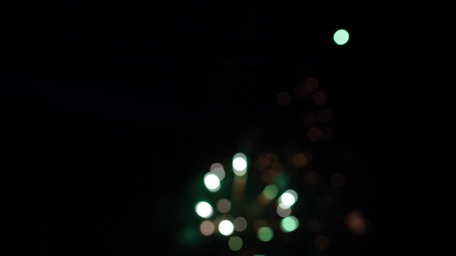 Bright colorful fireworks turn to multicolor bokeh lights at holiday dark summer night.