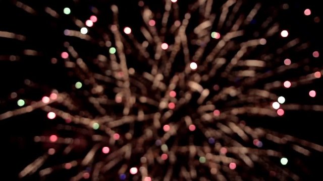 Bright colorful fireworks turn to multicolor bokeh lights at holiday dark summer night.