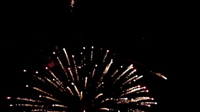 Bright colorful fireworks turn to multicolor bokeh lights at holiday dark summer night.