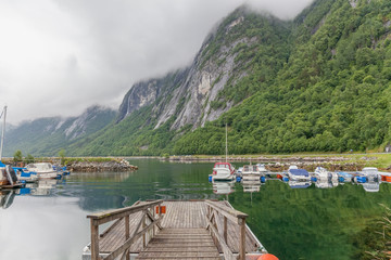 Molde, Norway - June 07, 2016: Fishing boats at the pier reflected in water with mountain in the background Norway