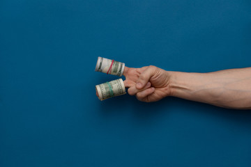 Hand holds money on a blue background.