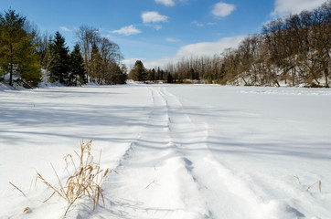 Frozen snow covered pond with snowmobile tracks