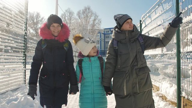 Three Schoolgirls walk home from school together on a Sunny winter day.