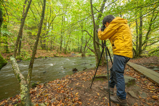 female photographer takes pictures of a beautiful view of the river and forest, selective focus, long exposure