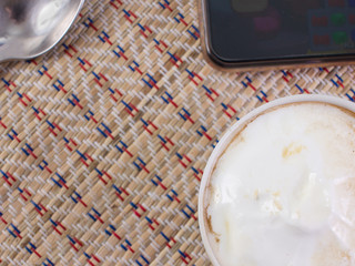 coffee with milk spoon phone on background