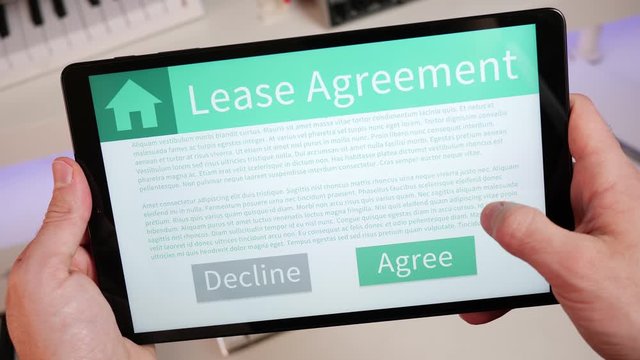 Reading and pressing the AGREE button at the end of a lease agreement on a tablet screen. Digital contract being accepted.
