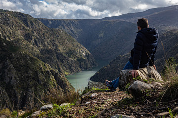 Naklejka premium person with blue jacket and glasses on his head, admiring the canyons of the sil from a viewpoint