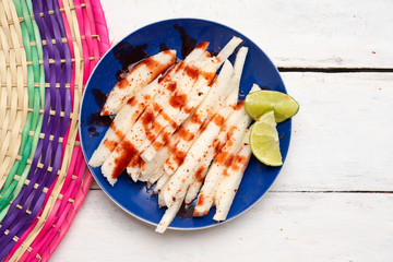 Mexican jicama  cutted with chili powder and piquant sauce on white background