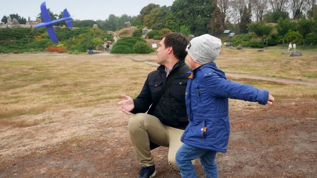4k video of happy cheerful young father launching toy airplane at the park