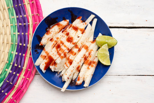 Mexican jicama  cutted with chili powder and piquant sauce on white background