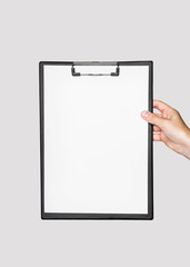 a clipboard with white empty sheet of paper in female hand on gray isolated background. Mockup, copy space, template for text