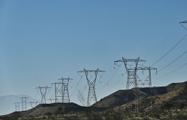 Line of High Tension Line Power Transmission Towers along Desert Hills in California