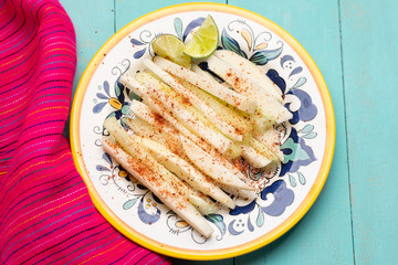 Mexican jicama and cucumber cutted with chili powder on turquoise background