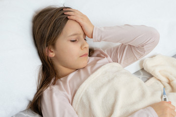 pretty girl lies sick in bed, feeling sick, fever and headache high temperature
