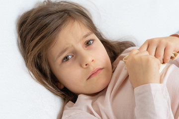 pretty girl lies sick in bed, feeling sick, fever and headache high temperature