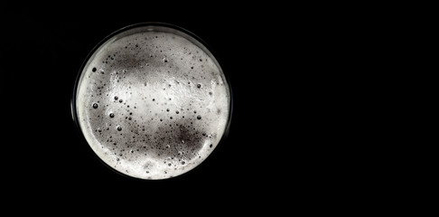 Foamy beer, top view. Glass of beer isolated on black background.