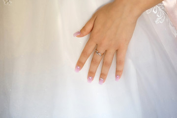 Photo of the brides hands with a wedding ring on a white dress background, there is a place for text, wedding day, a beautiful white dress, preparation for the meeting of the groom