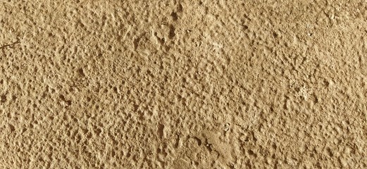 Beautiful sandstone, compacted sand. Stone texture on an old marble monument. Bright yellow color, rough surface, individual damage on the plane. Evening sunshine. Ancient architecture.