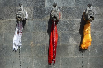 Water Fountain with 3 pipes coming out of stone wall wrapped with colourful Nepalese Scarfs on Annapurna Circuit Trek in Nepal Himalaya Mountains