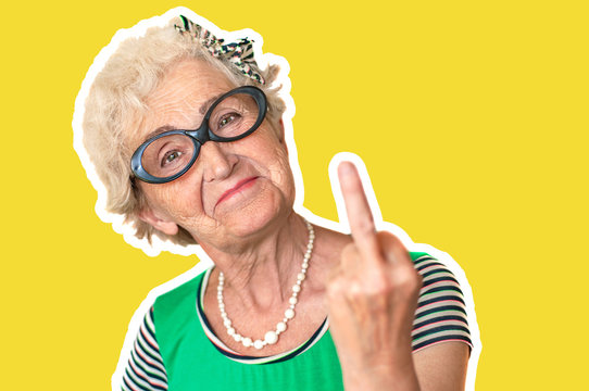 An older woman with an angry facial expression shows fuck you. Isolated The concept of discontent and protest of old woman . Yellow background, stroke.