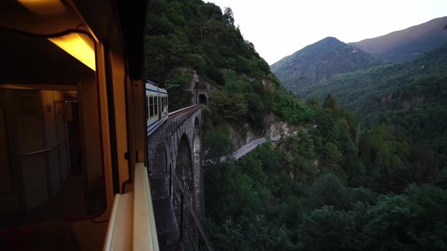 Scenic Centovalli Railway Locarno to Domodossola train on famous bridge. Swiss Alps. Slow motion. Ticino, Switzerland summer tourism.