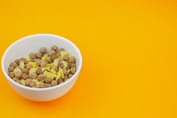Chocolate cereal and corn flakes in white cup on orange texture