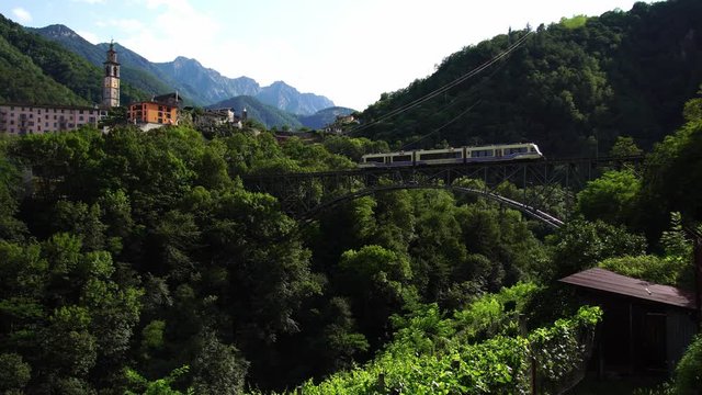 Famous scenic Centovalli railway train crossing bridge. between Domodossola & Locarno. Ticino Switzerland. Swiss Alps in summer, 4k.