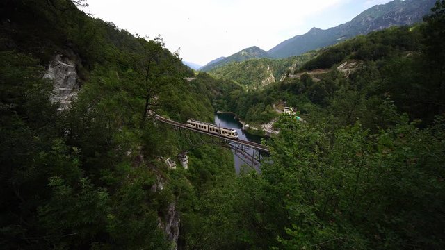 Famous scenic Centovalli railway train crossing bridge. between Domodossola & Locarno. Ticino Switzerland. Swiss Alps in summer, 4k.