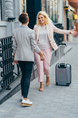 Business woman with suitcase meet her colleague on the street