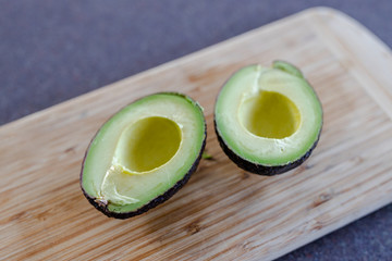 healthy ingredients, avocado cut in halves on cutting board